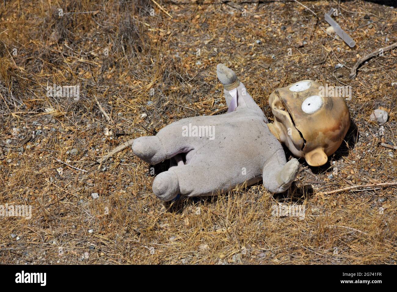 Weggeworfene Puppe mit großen Augen auf der Seite eines kalifornischen Highways, die in der Dürresonne backte, nachdem sie von einem vorbeifahrenden Auto verloren gegangen war Stockfoto