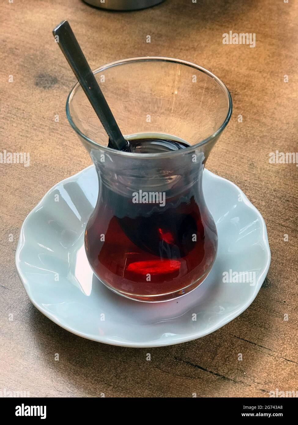 Typische Tasse türkischer Tee, serviert in einem Glas mit einem Löffel in einem Straßencafé in Istanbul, Türkei Stockfoto