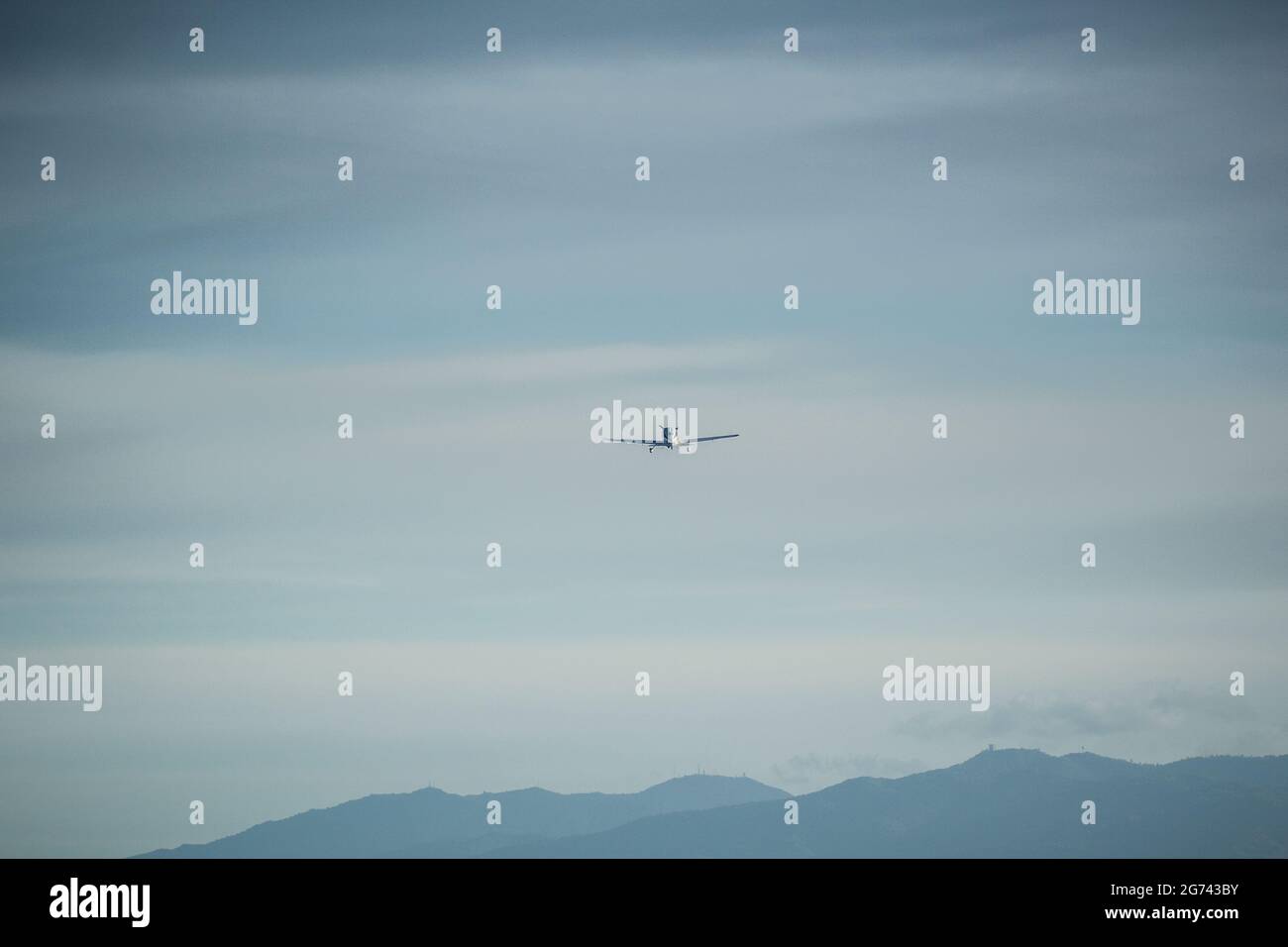 Kleines Flugzeug zentriert, das an bewölktem/trüben Tag tief in Richtung Kamera fliegt, mit Santa Cruz-Berglandschaft im Hintergrund. Landung am Flughafen Palo Alto. Stockfoto