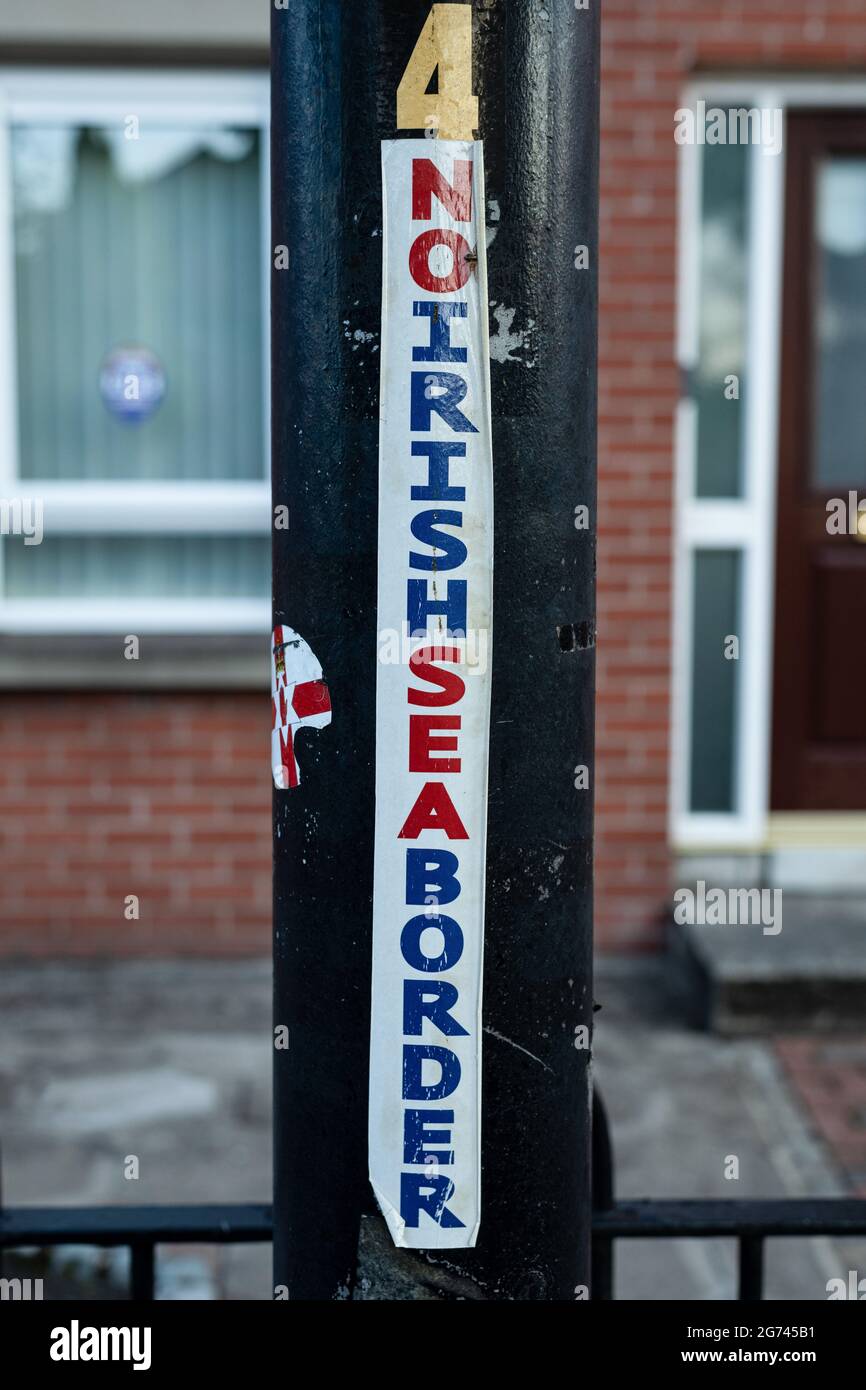 Ein Aufkleber, der in der loyalistischen Gegend Sandy Roe in Belfast gefunden wurde und auf einem Laternenpfahl angebracht ist, lautet „Keine Grenze an der Irischen See“ als Reaktion auf die Post-Brexit-Protokolle, die die unionistische Bevölkerung Nordirlands als Distanz zum Vereinigten Königreich empfindet und die Handelslogistik beeinträchtigt. Vorbereitungen anstelle der Lagerfeuernacht am 11. Juli in Belfast vor den jährlichen Märschen der Oranje Order vom 12. Juli. In diesem Jahr jährt sich die Gründung Nordirlands zum hundertsten Mal und ist gleichzeitig der erste zugelassene Orangen-Marsch seit Beginn der Pandemie. Die Marschsaison ist in einer angespannten Zeit gefallen, in der sich der Brexit für die USA einstellt Stockfoto