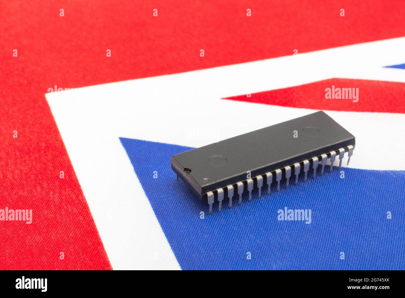 Nahaufnahme des integrierten Schaltkreises/EPROM-Chips auf der kleinen UK Union Jack-Flagge. Bei Halbleitermangel in Großbritannien, Abhängigkeit von britischen Chips, Start-ups von britischen Chips. Stockfoto