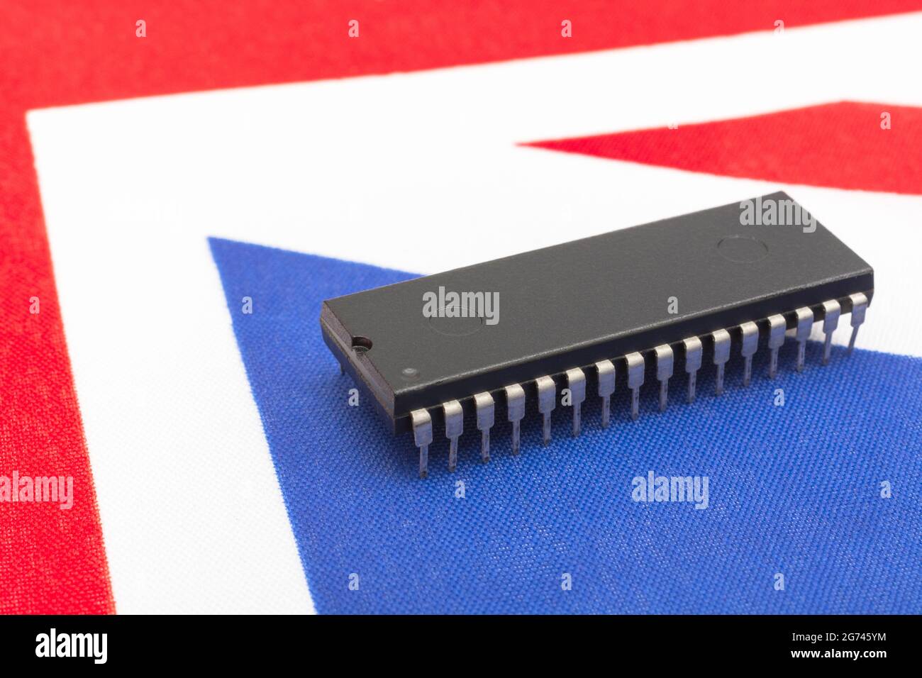 Nahaufnahme des integrierten Schaltkreises/EPROM-Chips auf der kleinen UK Union Jack-Flagge. Bei Halbleitermangel in Großbritannien, Abhängigkeit von britischen Chips, Start-ups von britischen Chips. Stockfoto