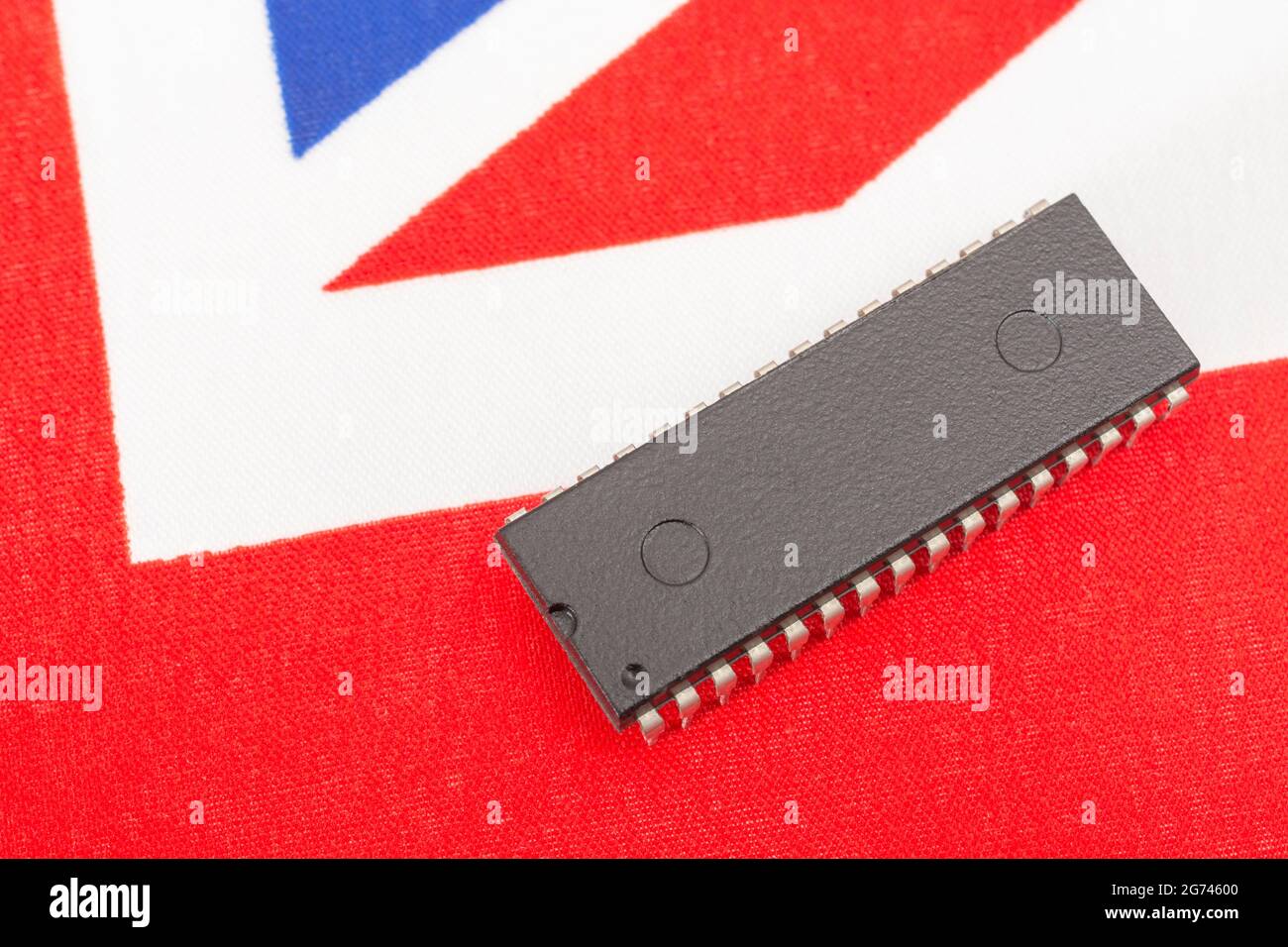 Nahaufnahme des integrierten Schaltkreises/EPROM-Chips auf der kleinen UK Union Jack-Flagge. Bei Halbleitermangel in Großbritannien, Abhängigkeit von britischen Chips, Start-ups von britischen Chips. Stockfoto