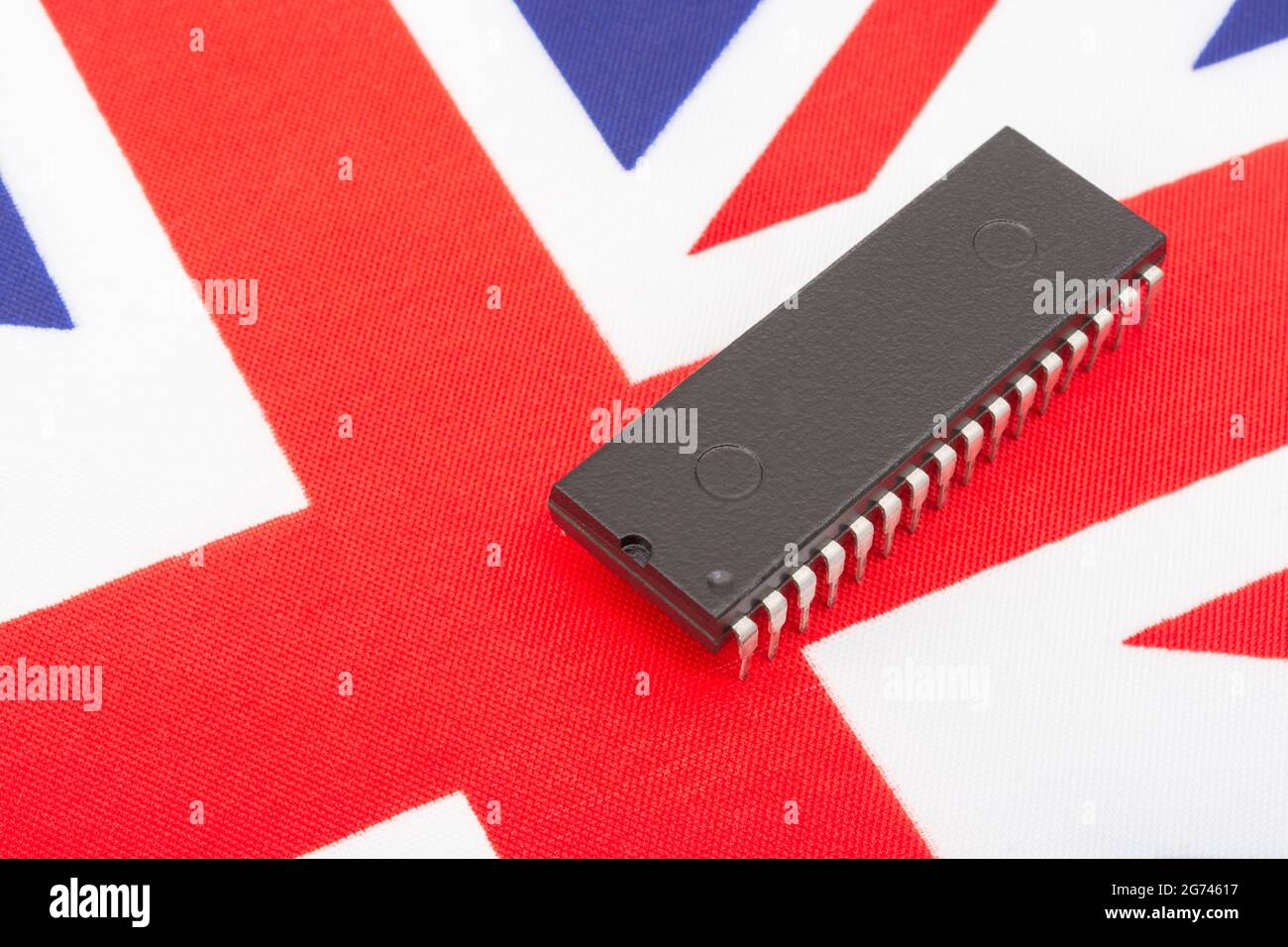 Nahaufnahme des integrierten Schaltkreises/EPROM-Chips auf der kleinen UK Union Jack-Flagge. Bei Halbleitermangel in Großbritannien, Abhängigkeit von britischen Chips, Start-ups von britischen Chips. Stockfoto