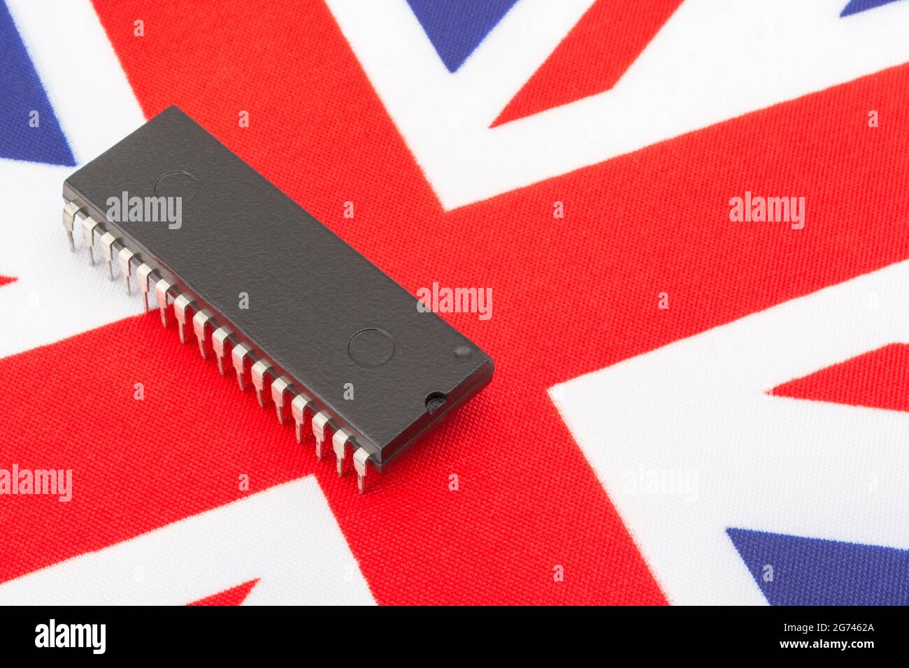 Nahaufnahme des integrierten Schaltkreises/EPROM-Chips auf der kleinen UK Union Jack-Flagge. Bei Halbleitermangel in Großbritannien, Abhängigkeit von britischen Chips, Start-ups von britischen Chips. Stockfoto