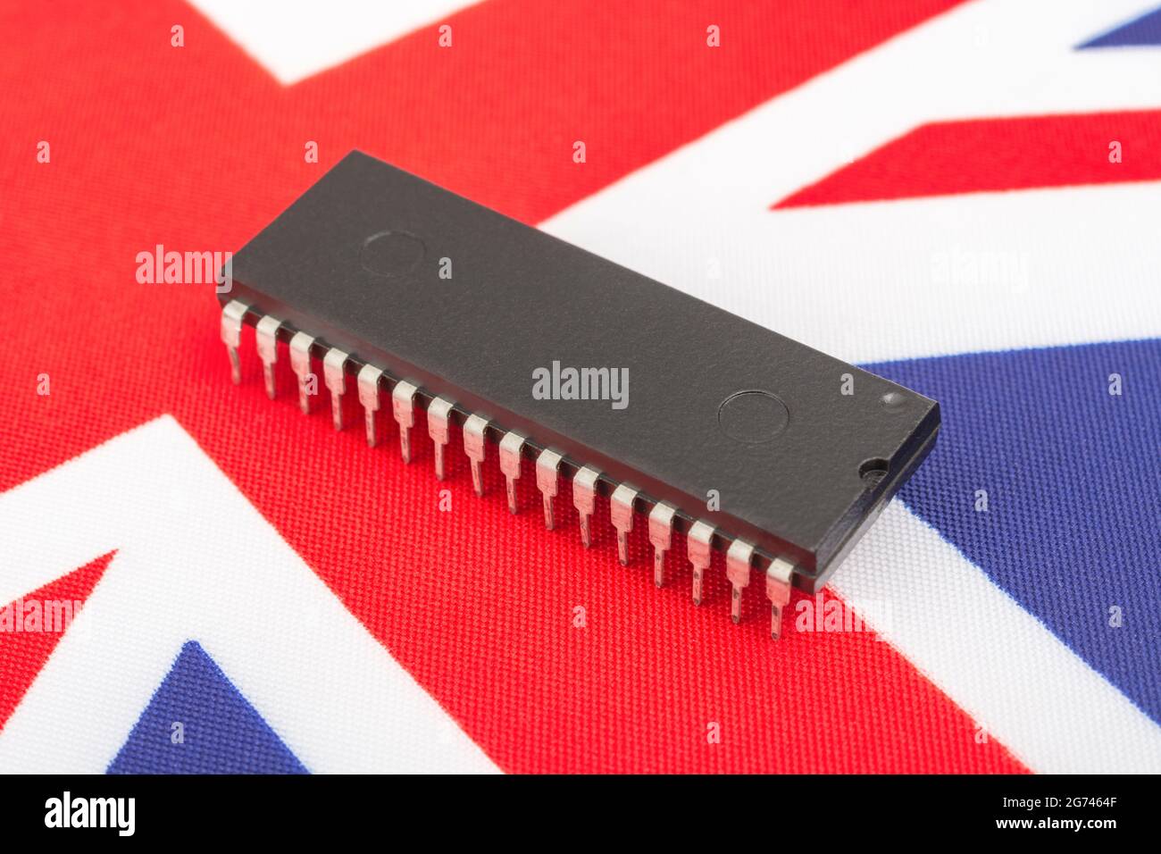 Nahaufnahme des integrierten Schaltkreises/EPROM-Chips auf der kleinen UK Union Jack-Flagge. Bei Halbleitermangel in Großbritannien, Abhängigkeit von britischen Chips, Start-ups von britischen Chips. Stockfoto