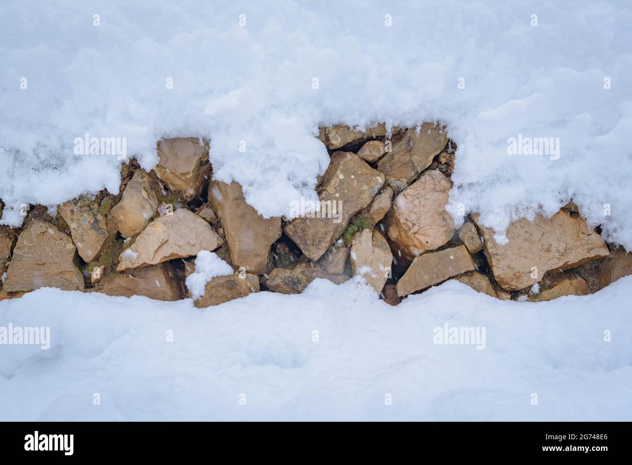 Schneebedeckte Trockensteinmauer in einem Feld in der Nähe von Cornudella de Montsant (Priorat, Tarragona, Katalonien, Spanien) ESP: Pared de piedra seca cubierta de nieve Stockfoto