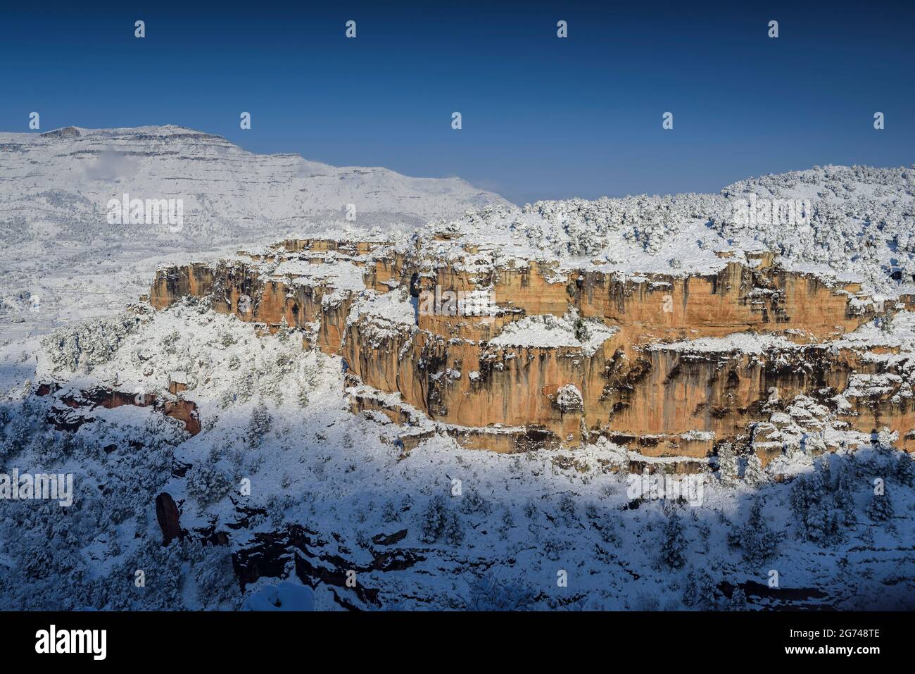 Schneebedeckte Siuranella-Klippen im Winter, vom Dorf Siurana aus gesehen. Im Hintergrund der Berg Montsant (Priorat, Tarragona, Katalonien, Spanien) Stockfoto