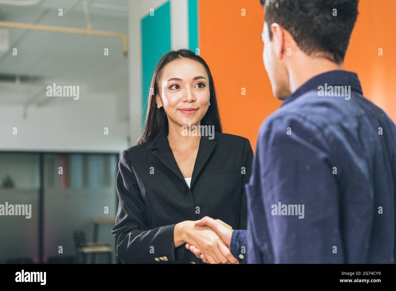Die Begrüßung der Geschäftsfrauen trifft einen Mann, der die Hand schüttelt und lächelnd den Kontakt für den Projektpartner im Büro anhält. Stockfoto
