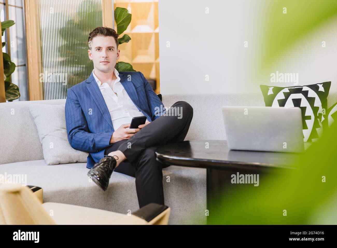 Smart schöner kaukasischer Geschäftsmann sitzen entspannen Wartebereich in modernen Büro. Stockfoto