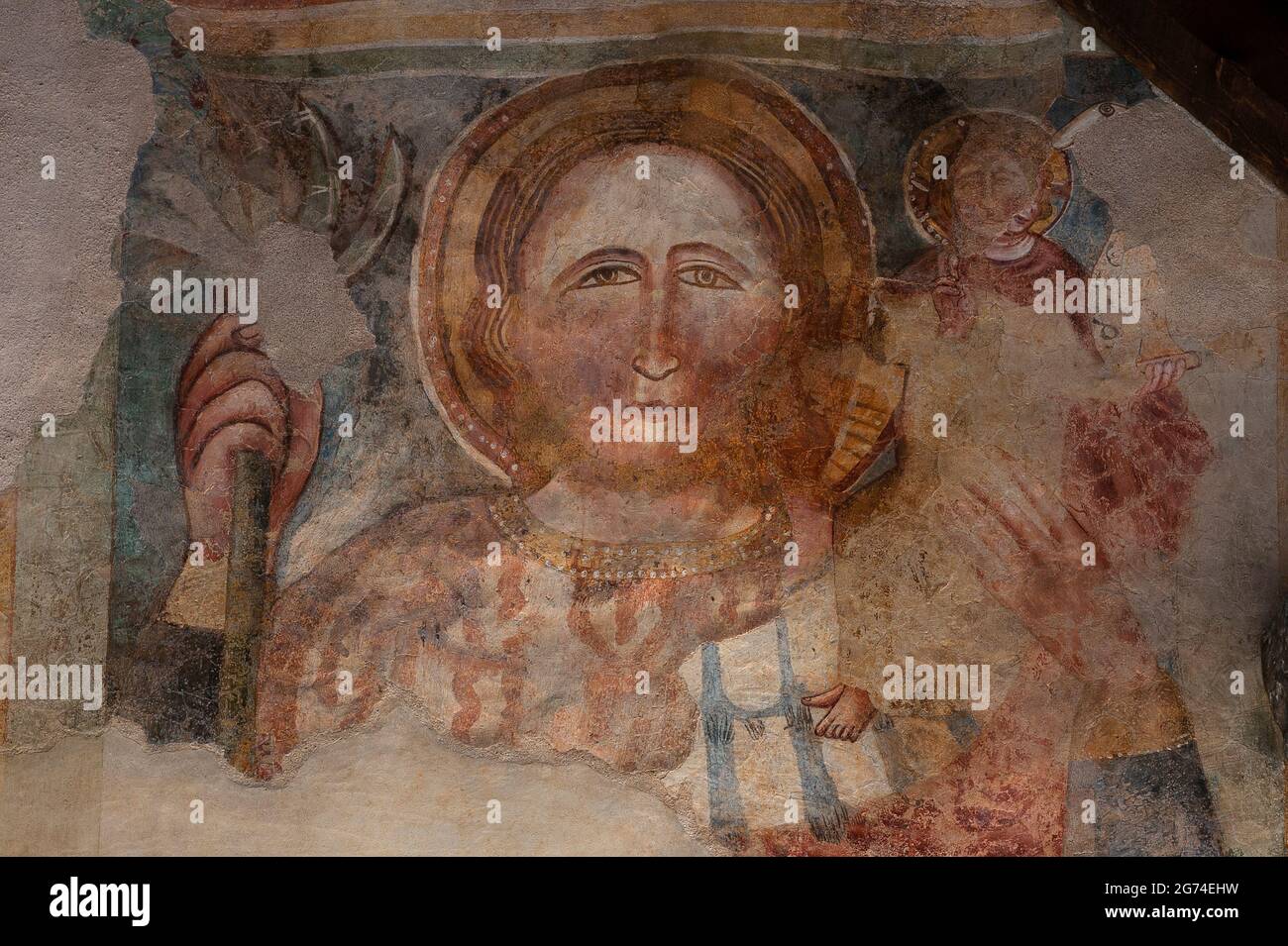 Der heilige Christoph trägt mit durchdringendem Blick das Christkind auf seiner Schulter. Detail des spätmittelalterlichen Freskos des wandernden lombardischen Künstlers, bekannt als Maestro di Sommacampagna, an der Westfront der 1300 Chiesa oder Chiesetta di San Tommaso Apostolo (Kirche des Apostels Thomas) in Cavedago, Trentino-Südtirol, Italien. Stockfoto