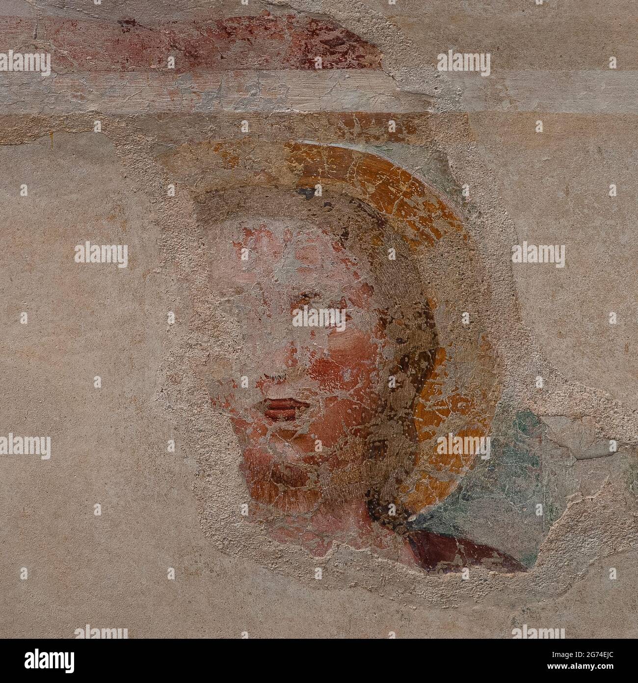 Gesicht eines heiligen. Detail des fragmentarischen Freskos aus dem Spätmittelalter oder Frührenaissance an der Westfront der Chiesa oder Chiesetta di San Tommaso Apostolo (Kirche des Apostels Thomas) Mitte der 1300er Jahre in Cavedago, Trentino-Südtirol, Italien. Die hervorragende Verarbeitung deutet darauf hin, dass das Fresko vielleicht von einem Anhänger des einflussreichen florentinischen Künstlers Giotto di Bondone (1267–1337) gemalt wurde. Stockfoto