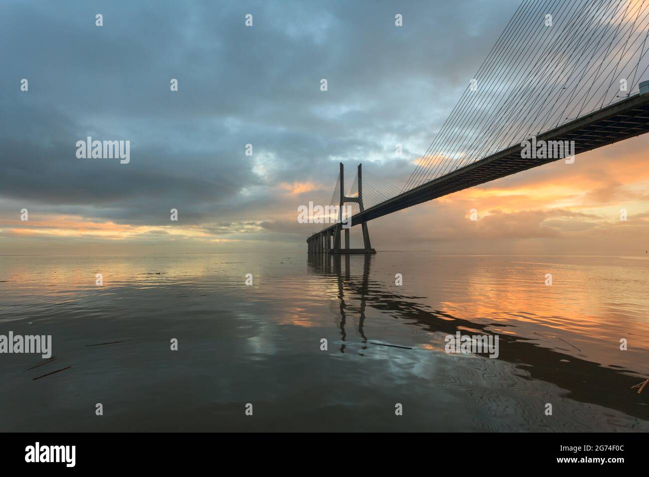 Hintergrund mit buntem Sonnenaufgang auf der Lissabon-Brücke. Die Vasco da Gama Brücke ist ein Wahrzeichen und eine der längsten Brücken der Welt. Urban lan Stockfoto