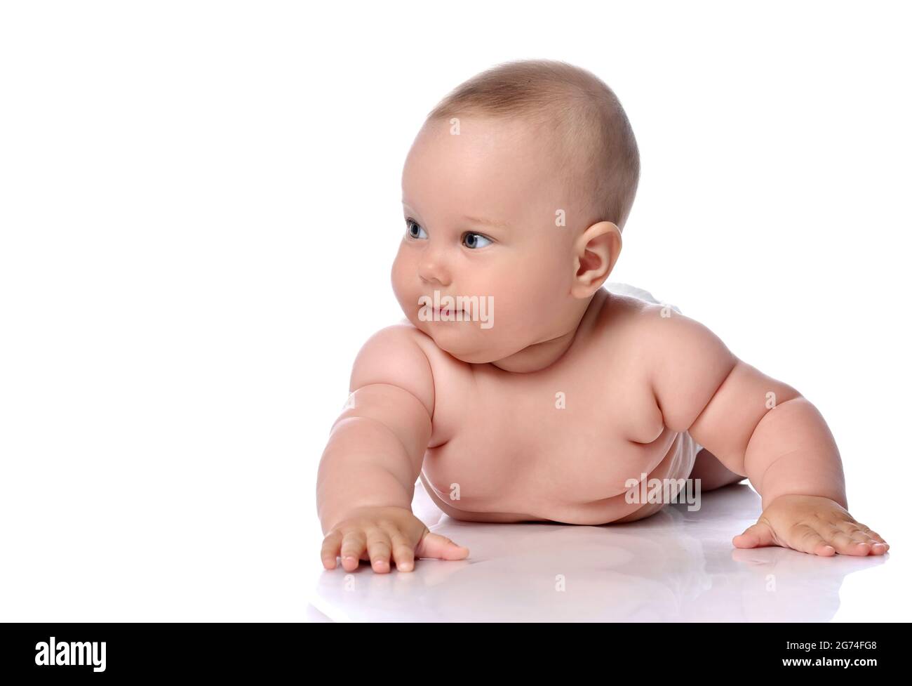 Schlaue, neugierige Kleinkind Baby Mädchen Kind in Windel liegt auf ihrem Bauch, Bauch und schaut zur Seite Stockfoto