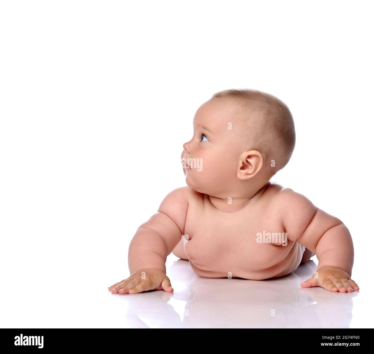 Neugieriges Kleinkind Baby Baby Mädchen Kind in Windel liegt auf ihrem Bauch, den Bauch gelehnt, steigt auf die Hände und schaut zur Seite Stockfoto