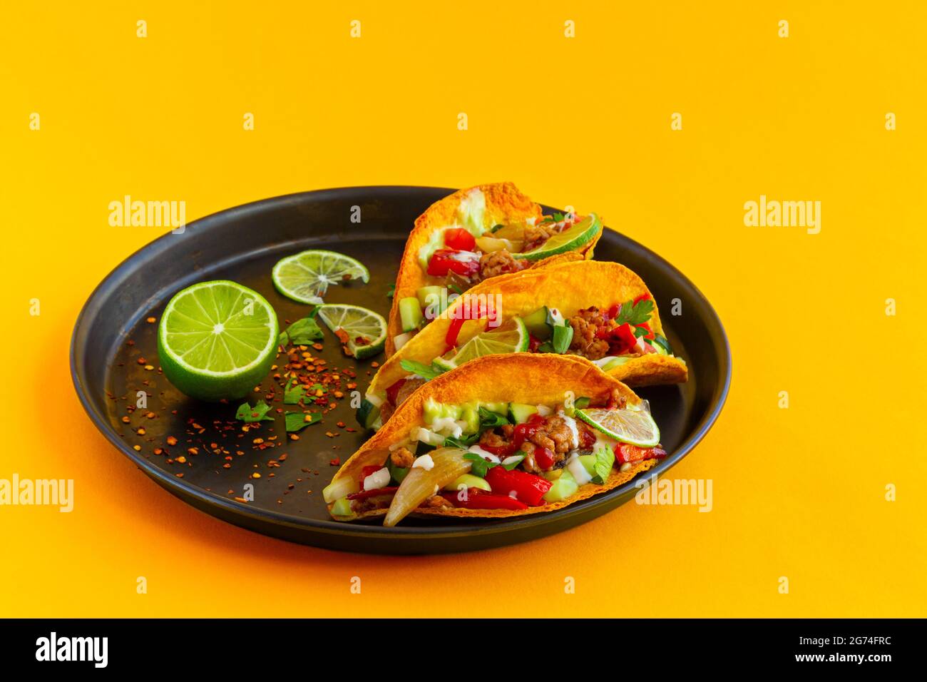 Mexikanischer Taco in schwarzer Pastete auf gelbem Hintergrund Stockfoto