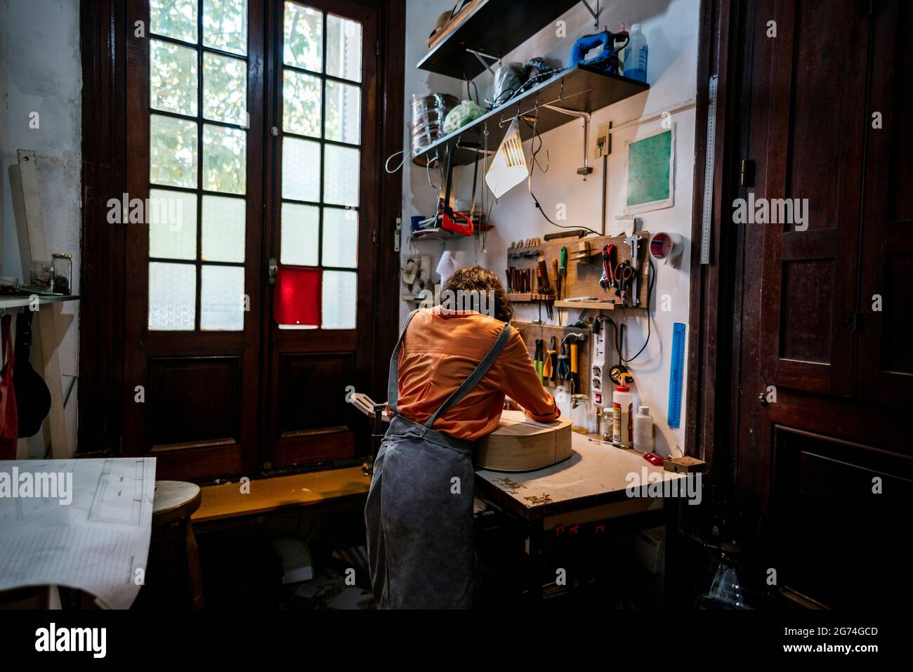 Unerkannte junge Frau in ihrer Geigenbauwerkstatt. Stockfoto