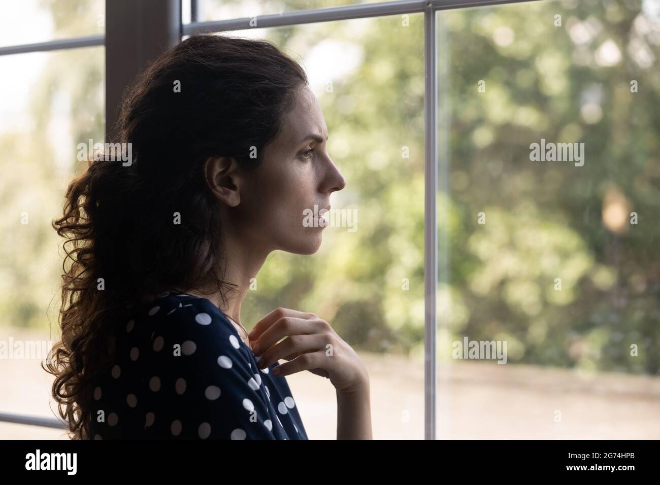 Frustrierte, depressive Millennials-Frau, die aus dem Fenster schaute Stockfoto