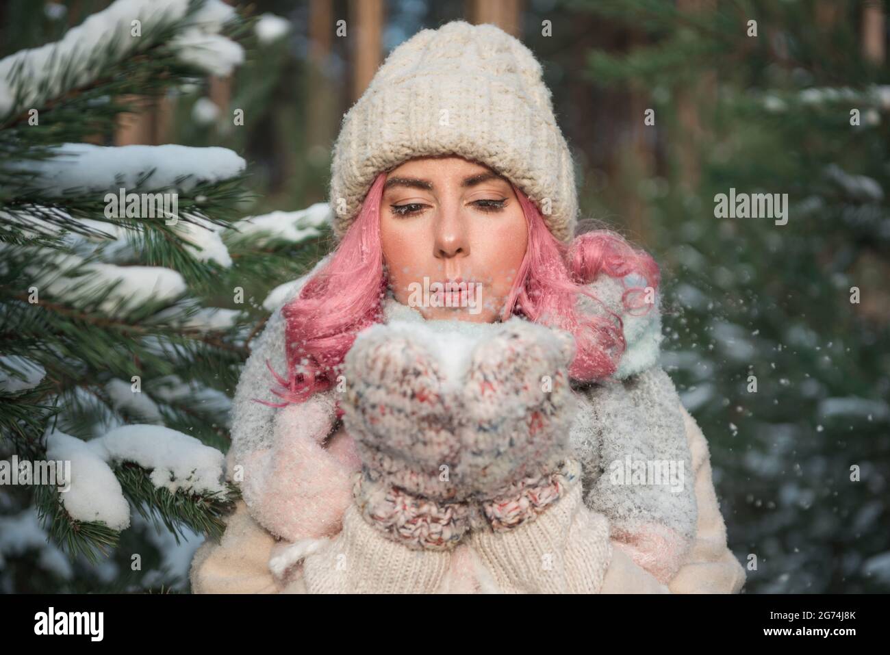 Schönes Mädchen mit rosa Haaren weht Schnee in den Händen Stockfoto