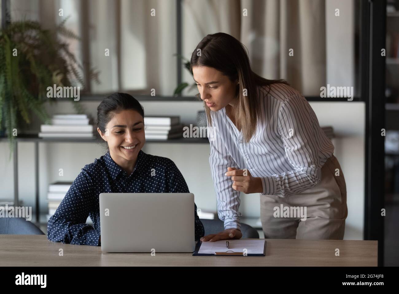 Glücklicher indischer Büroangestellter, der dem Chef das Ergebnis seiner Arbeit zeigt Stockfoto