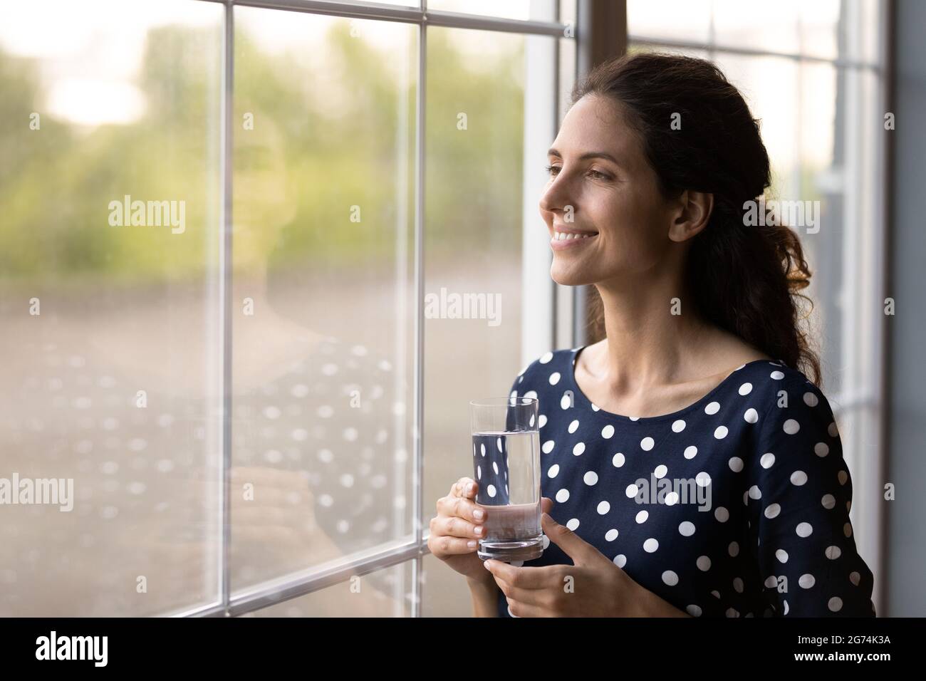 Glückliche lateinische Frau in zwangloser Holding Glas von reinem frischem Trinkwasser Stockfoto