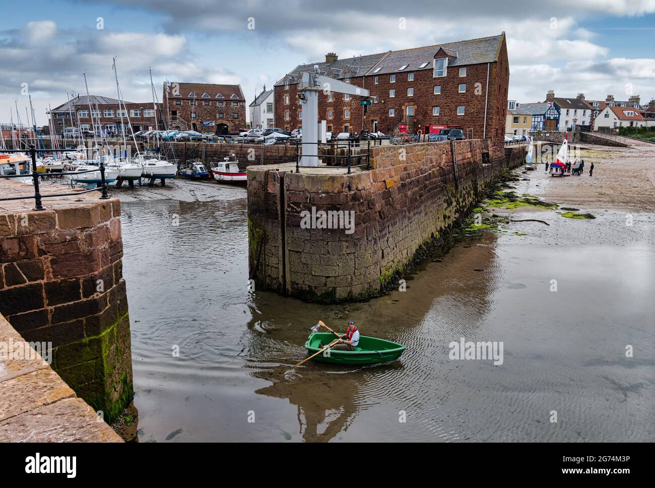 Mann rudert ein kleines Boot aus dem Hafen von North Berwick in West Bay East Lothian, Schottland, Großbritannien Stockfoto