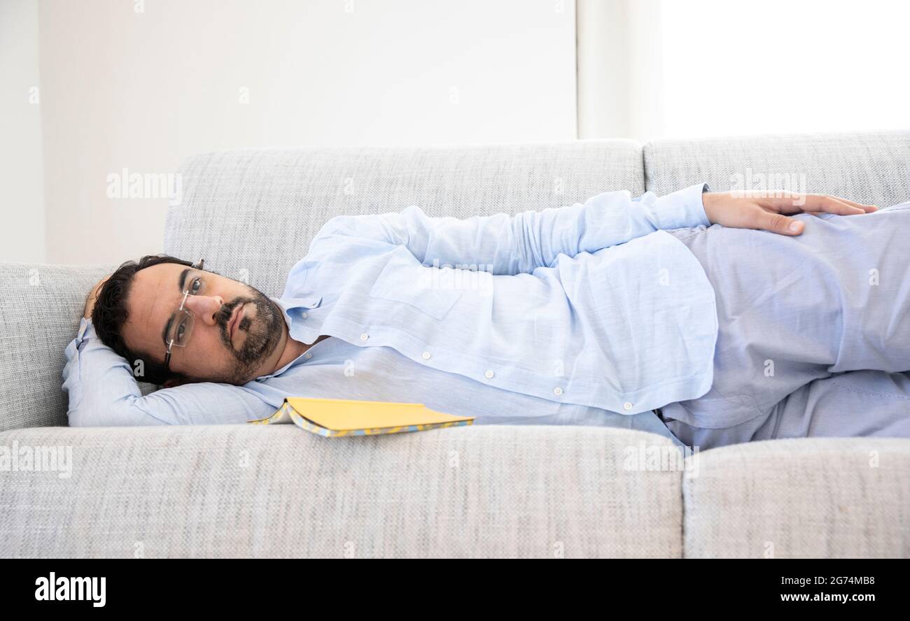 Mann mittleren Alters, der sich auf seinem Sofa ausruhte Stockfoto