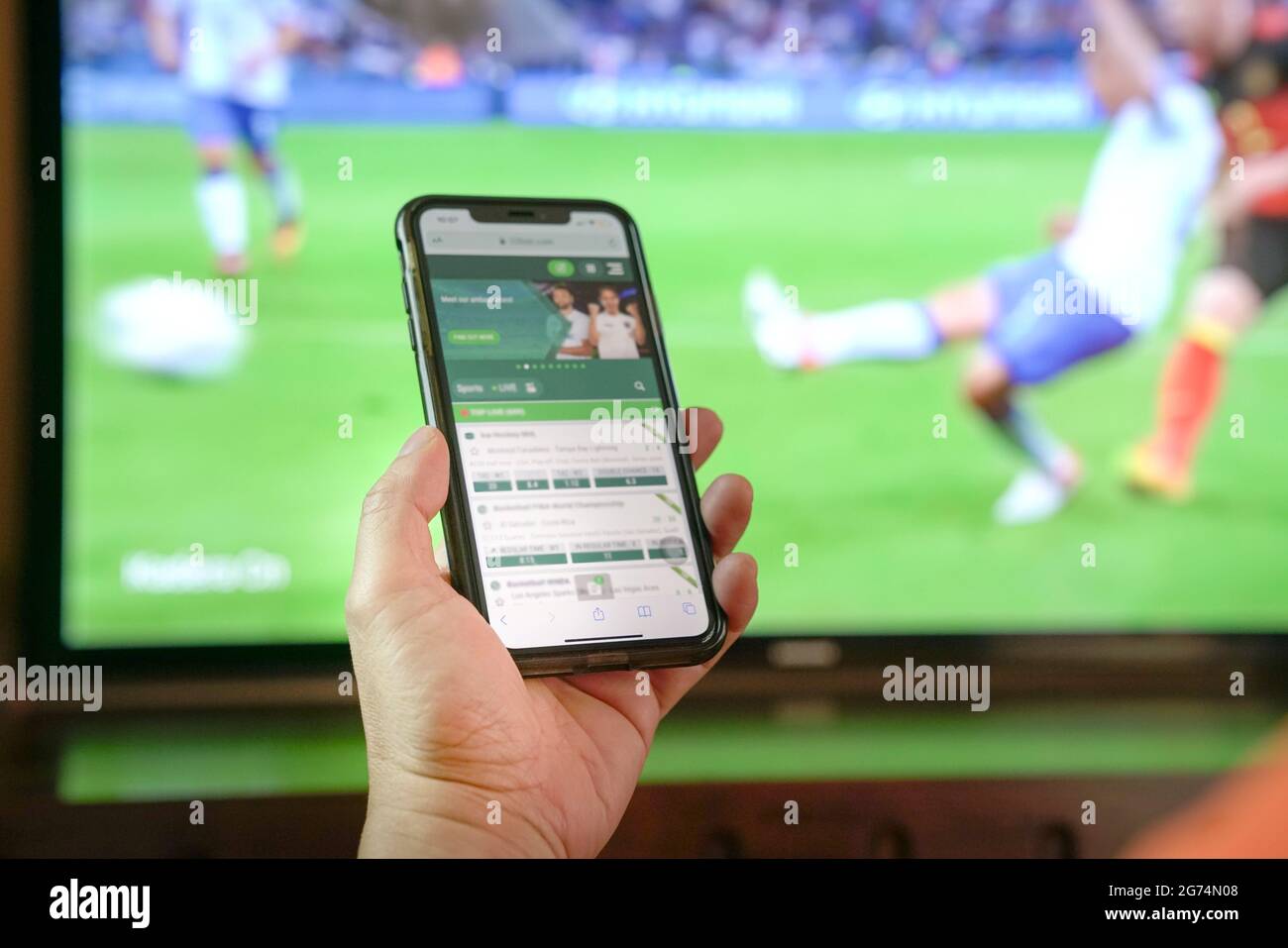 Sehen Sie sich Fußballspiele im Fernsehen an und wetten Sie über die App des Buchmachers über das Mobiltelefon. Nahaufnahme. Stockfoto