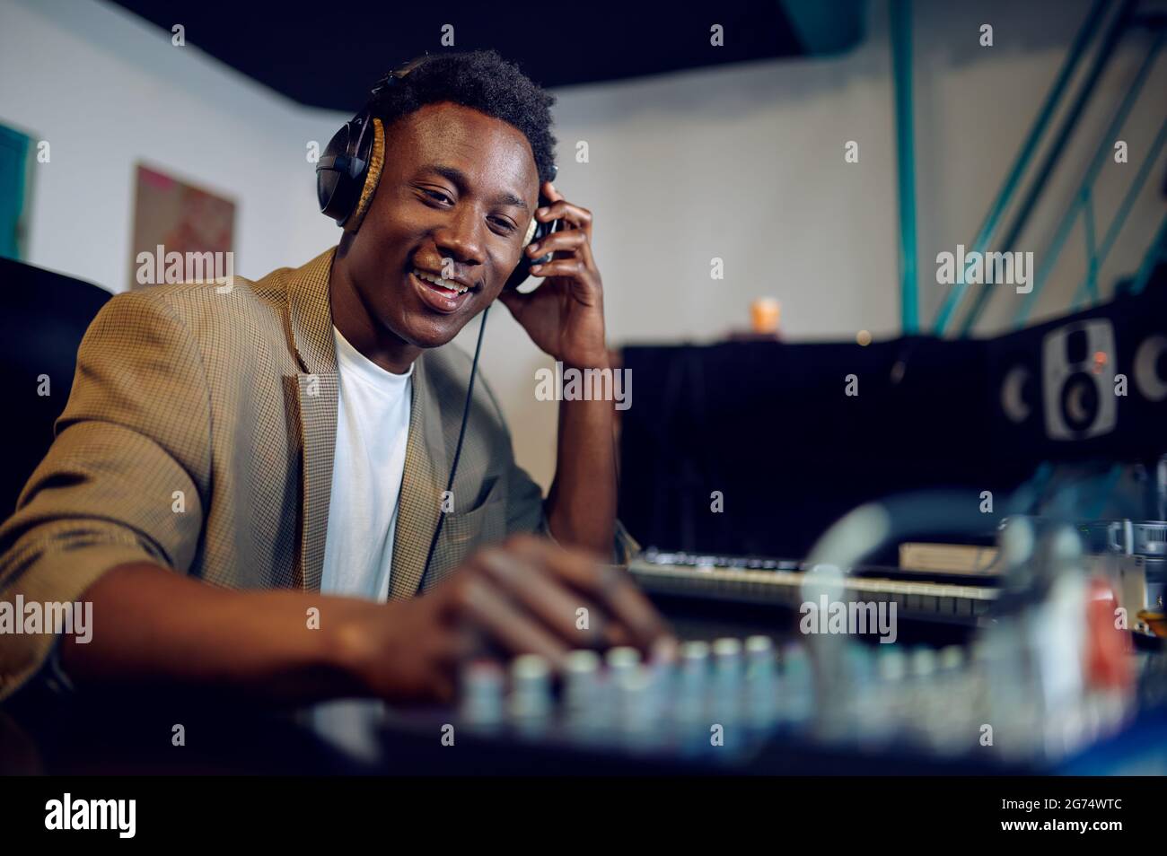 Fröhlicher, männlicher dj in Kopfhörern, Aufnahmestudio Stockfoto