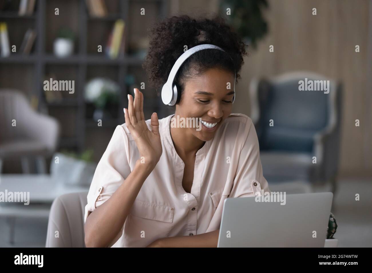 Nahaufnahme lächelnde afroamerikanische Frau in Kopfhörer winkende Hand Stockfoto