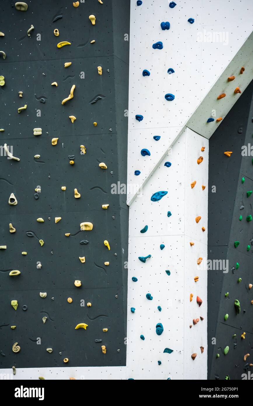 Künstliche Kletterwand mit verschiedenen farbigen Griffen im Outdoor-Fitness-Abenteuerpark. Stockfoto