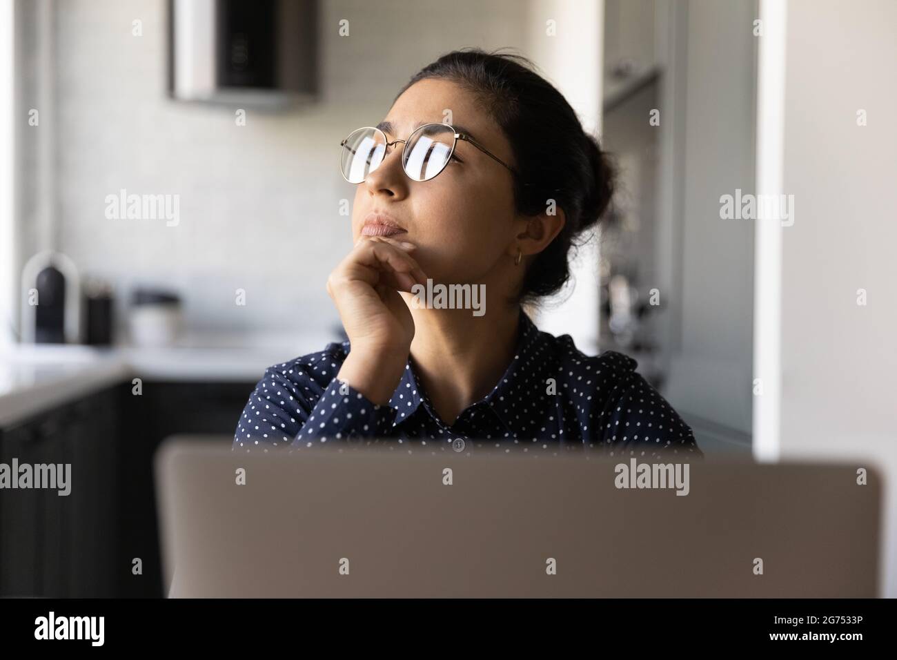 Nachdenkliche indische Mitarbeiterin, die von zu Hause aus am Laptop arbeitet Stockfoto