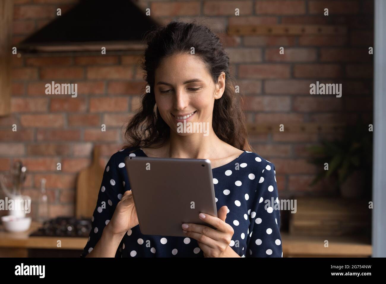 Glückliche hispanische Frau mit Computer-Tablet zu Hause Stockfoto