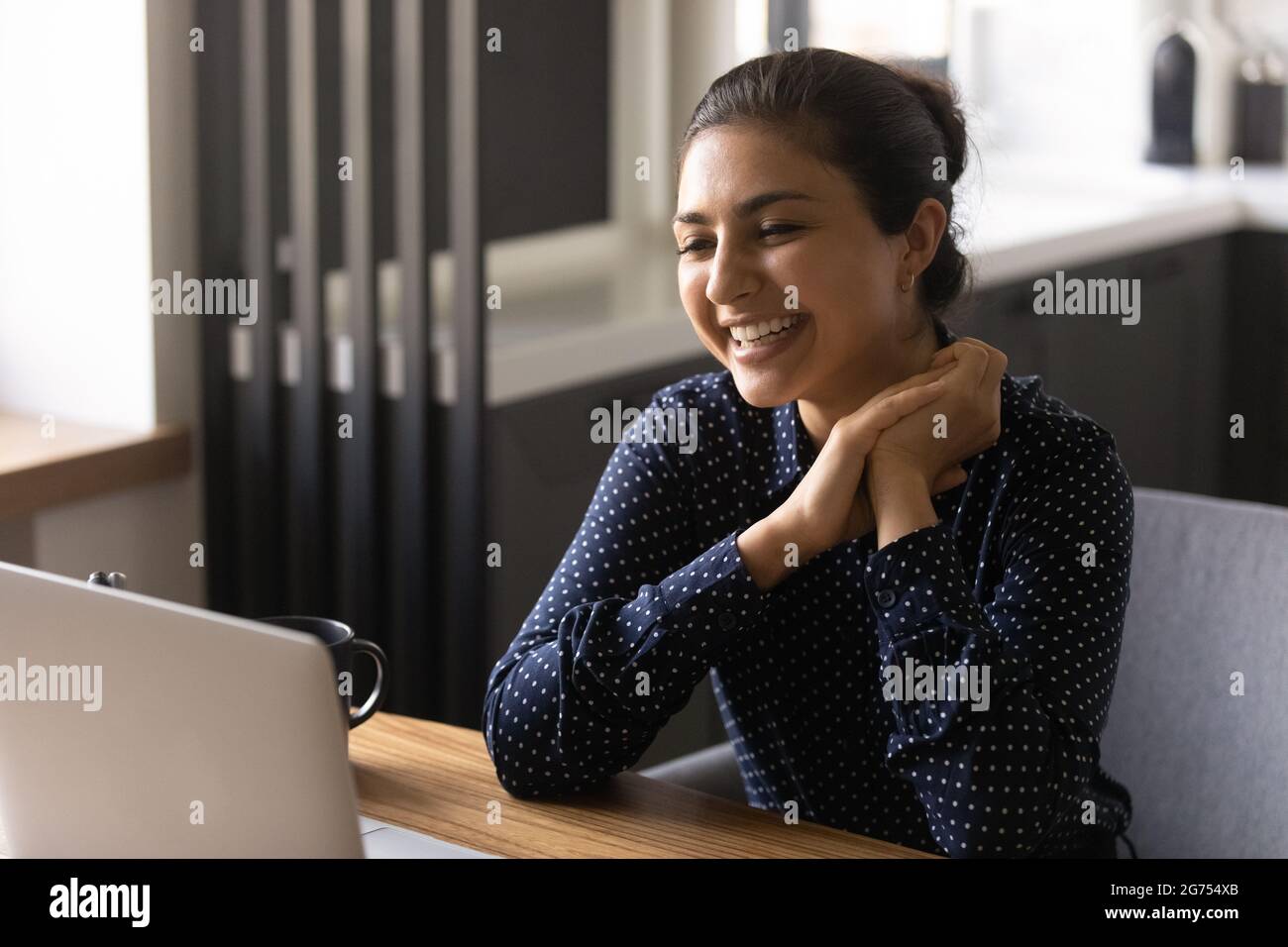 Glückliche indische Mitarbeiterin, die von zu Hause aus am Laptop arbeitet Stockfoto