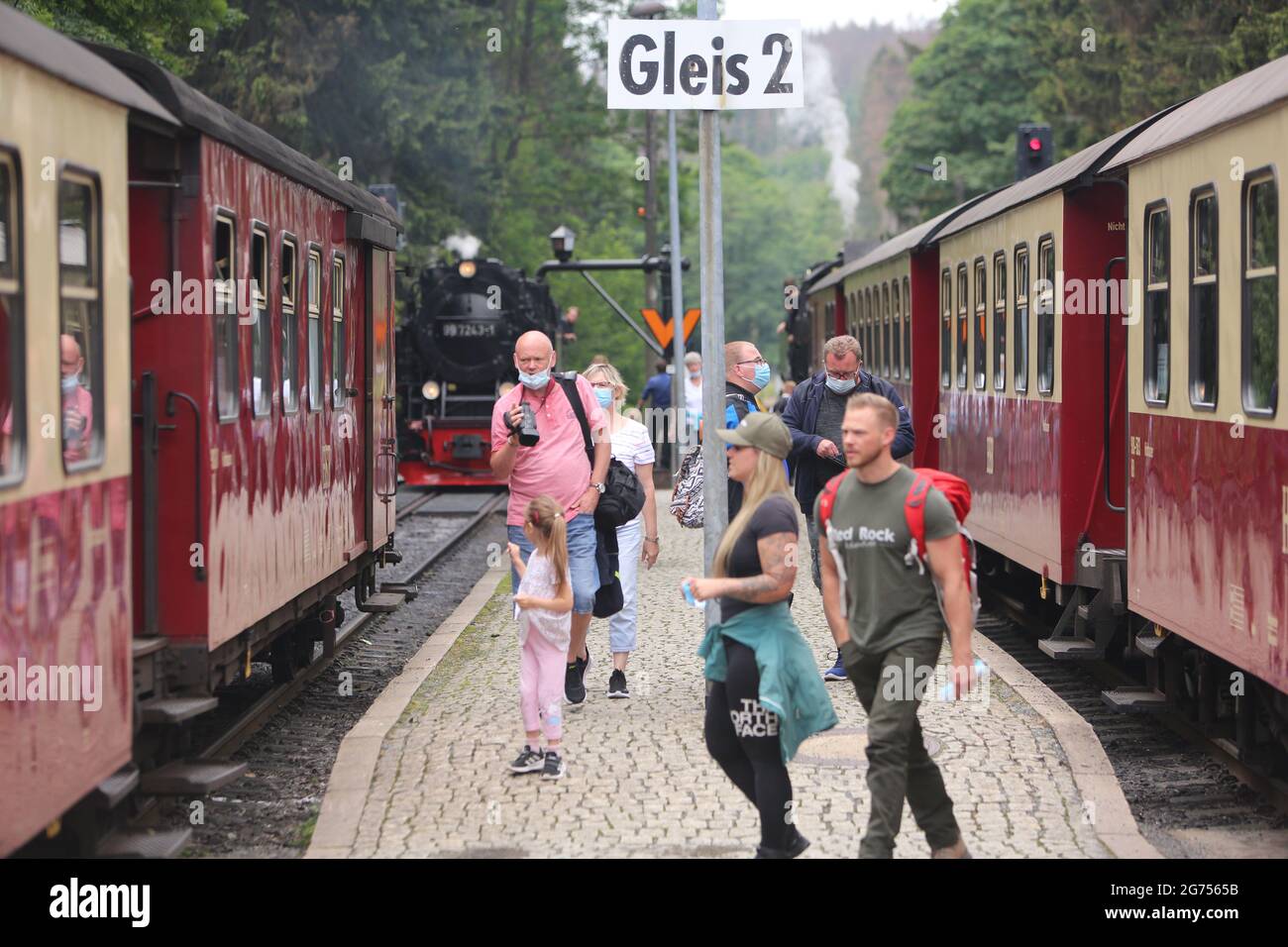 Schierke, Deutschland. Juli 2021. Passagiere stehen am Bahnhof und steigen in den Zug der Harzer Schmalspurbahn HSB. Die HSB führt den Sommerflugplan wieder uneingeschränkt aus. Zuvor wurden die Zugverbindungen für sieben Monate fast vollständig eingestellt. Mit Beginn der Ferienzeit steigt auch die Zahl der Passagiere wieder an. Quelle: Matthias Bein/dpa-Zentralbild/dpa/Alamy Live News Stockfoto