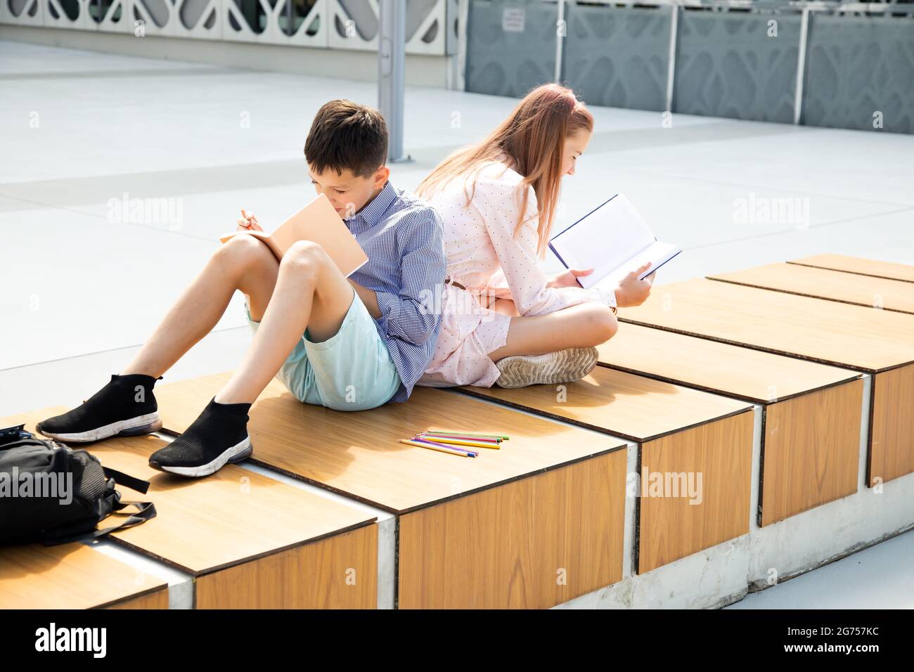Schüler Mädchen und Jungen Jugendliche 11 Jahre alt studieren auf dem Schulhof, lesen Buch und schreiben in Notebook Stockfoto