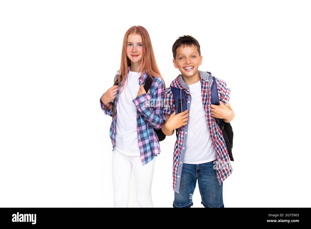 Junge und Mädchen Teenager 11 Jahre alt Schuljunge und Schülerin Blick auf die Kamera auf weißem Hintergrund mit Rucksack und lächelnd. In kariertes Hemd gekleidet, w Stockfoto