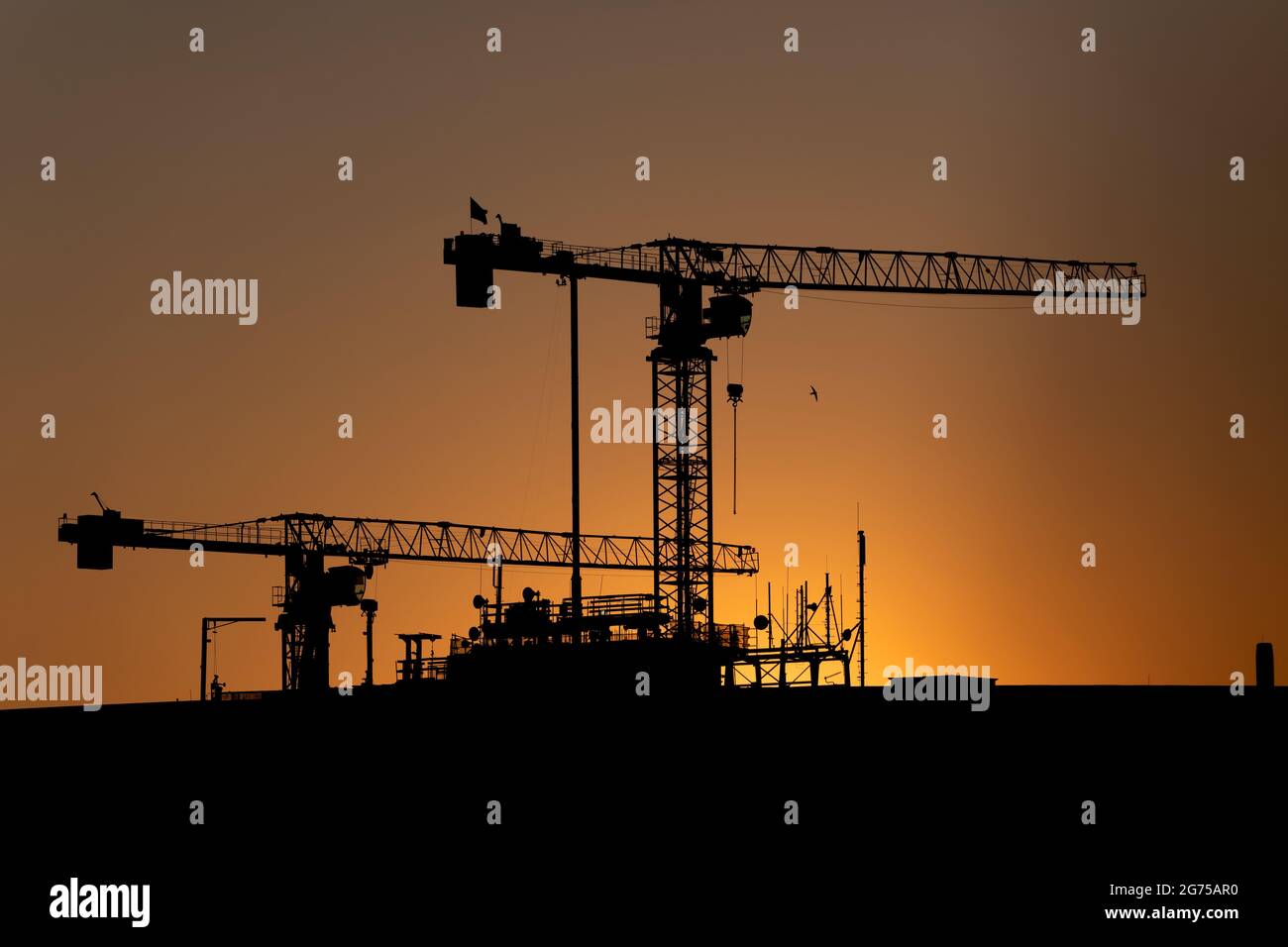 Krane Silhouette gegen Sonnenuntergang Himmel, Baustelle eines Bürogebäudes. Stockfoto