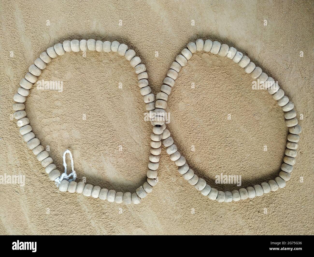 Eine Halskette aus Stein in der Form von Unendlichkeit auf dem Sand Stockfoto