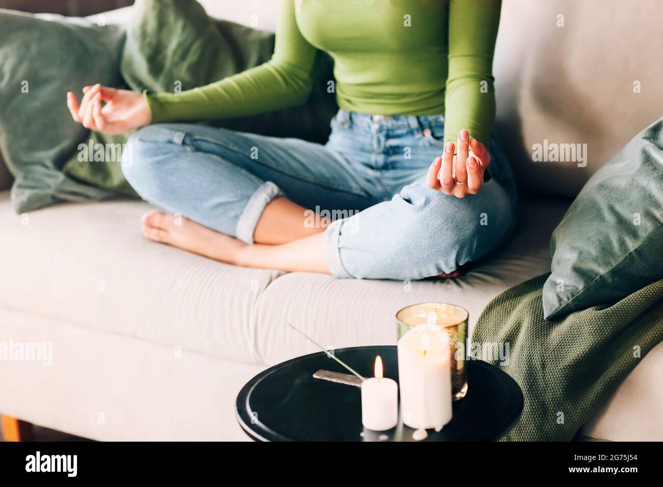 Unerkennbare Barfußfrau, die in Lotus-Pose auf dem Bett sitzt und während der Yoga-Sitzung zu Hause meditiert Stockfoto