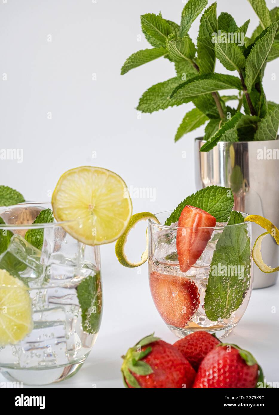 Glas mit Erdbeere, Limette, Eis und Minze. Mojito mit Rohrzucker. Weißer Boden. Erfrischender Sommerdrink. Ein Gefühl von Frische. Stockfoto