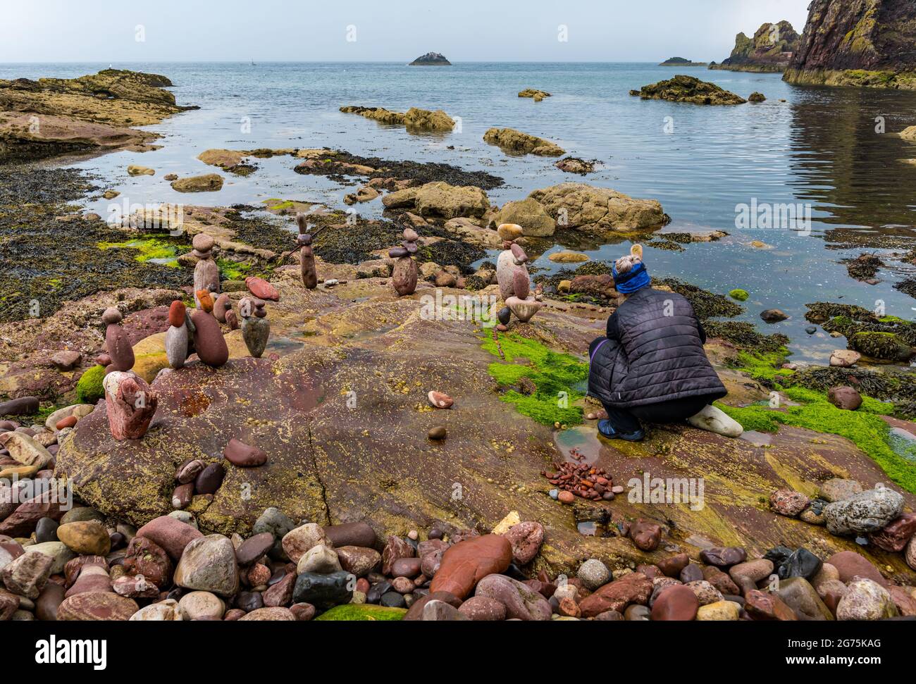 Dunbar, East Lothian, Schottland, Großbritannien, 11. Juli 2021. European Stone Stacking Championship: Am zweiten und letzten Tag treten die Landkünstler in einer künstlerischen Herausforderung an, in der sie 4 Stunden Zeit haben, um eine Felsskulptur zu erschaffen. Im Bild: Steinbilanzen der Teilnehmerin Caroline Walker, die in der Regel Arbeiten im Wasser erstellt, die hier so konzipiert sind, dass sie bei Flut zusammenbrechen Stockfoto