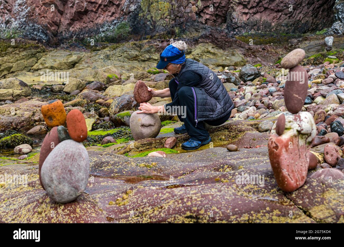 Dunbar, East Lothian, Schottland, Großbritannien, 11. Juli 2021. European Stone Stacking Championship: Am zweiten und letzten Tag treten die Landkünstler in einer künstlerischen Herausforderung an, in der sie 4 Stunden Zeit haben, um eine Felsskulptur zu erschaffen. Im Bild: Steinbilanzen der Teilnehmerin Caroline Walker, die in der Regel Arbeiten im Wasser erstellt, die hier so konzipiert sind, dass sie bei Flut zusammenbrechen Stockfoto