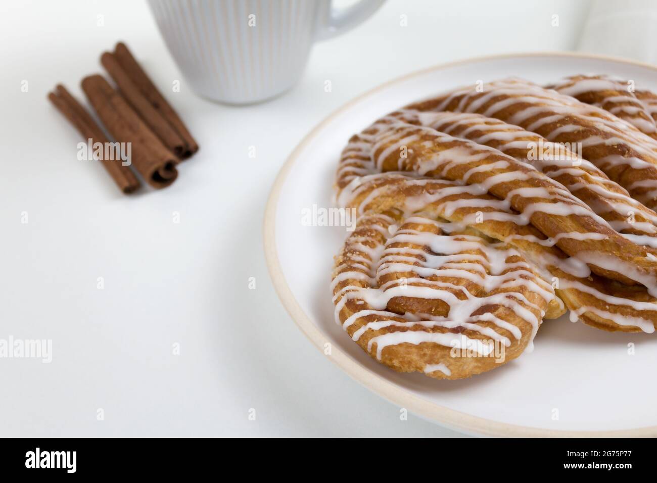 Zimtrollen oder Zimtbrötchen Dessert auf Teller mit weißer Tasse Kaffee. Klassische amerikanische oder französische Bäckereien. Stockfoto