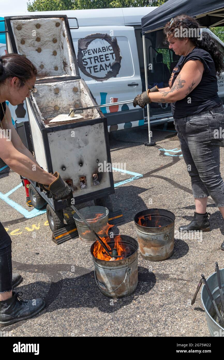 Detroit, Michigan - Mitglieder des Pewabic Pottery Street Teams demonstrieren die japanische Technik des Raku-Feuers von Töpferwaren auf einem Gemeinschaftskunstwerk und einem Mu Stockfoto