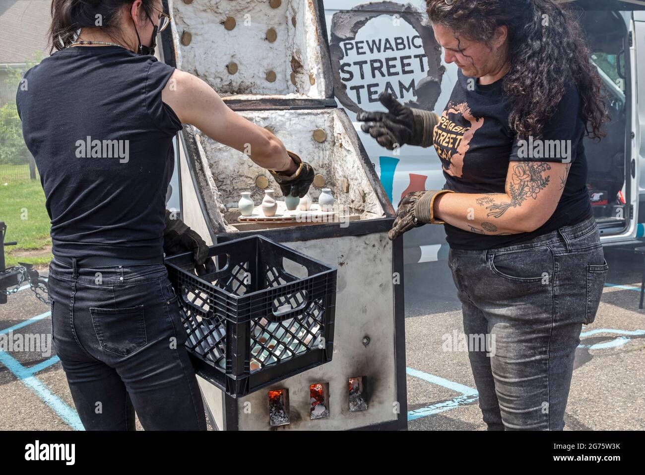 Detroit, Michigan - Mitglieder des Pewabic Pottery Street Teams demonstrieren die japanische Technik des Raku-Feuers von Töpferwaren auf einem Gemeinschaftskunstwerk und einem Mu Stockfoto