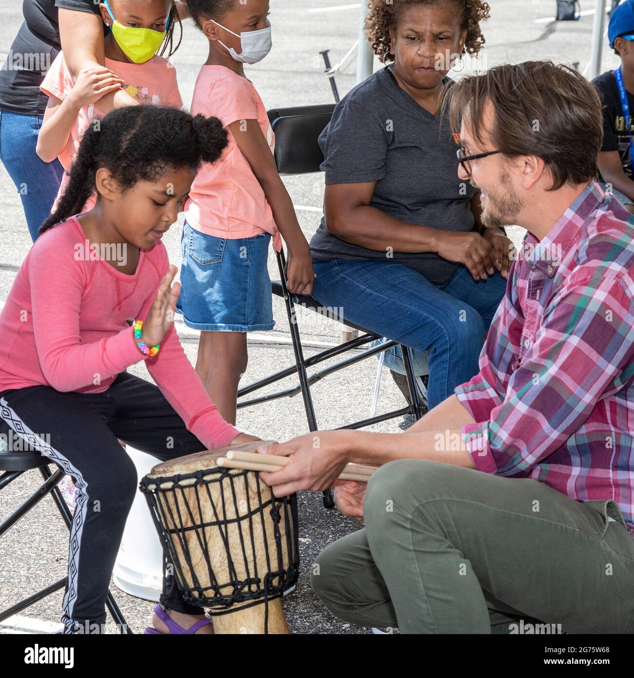 Detroit, Michigan - Kinder lernen auf einem Kunst- und Musikfestival Trommeln. Ben Piper (rechts), Musiklehrer an den Detroit Public Schools, Stockfoto