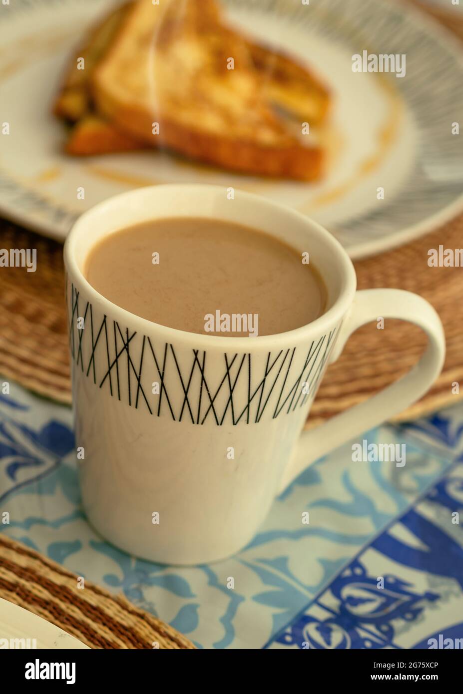 Eine weiße Tasse dampfenden Kaffee Latte, begleitet von französischem Toast zum Frühstück oder Brunch Stockfoto