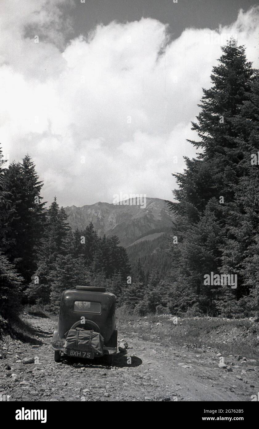 1935, historisch, ein Auto der Zeit, mit einem britischen Kennzeichen, gong auf einer felsigen, Schotterpiste hoch auf einem Waldgebiet der Sudeten oder Sudetenberge, Sudetenland, Tschechoslowakei. Sie sind der höchste Teil des so genannten Böhmischen Massivs, einer Reihe von Bergketten, die Teile mitteleuropas bedecken. Stockfoto