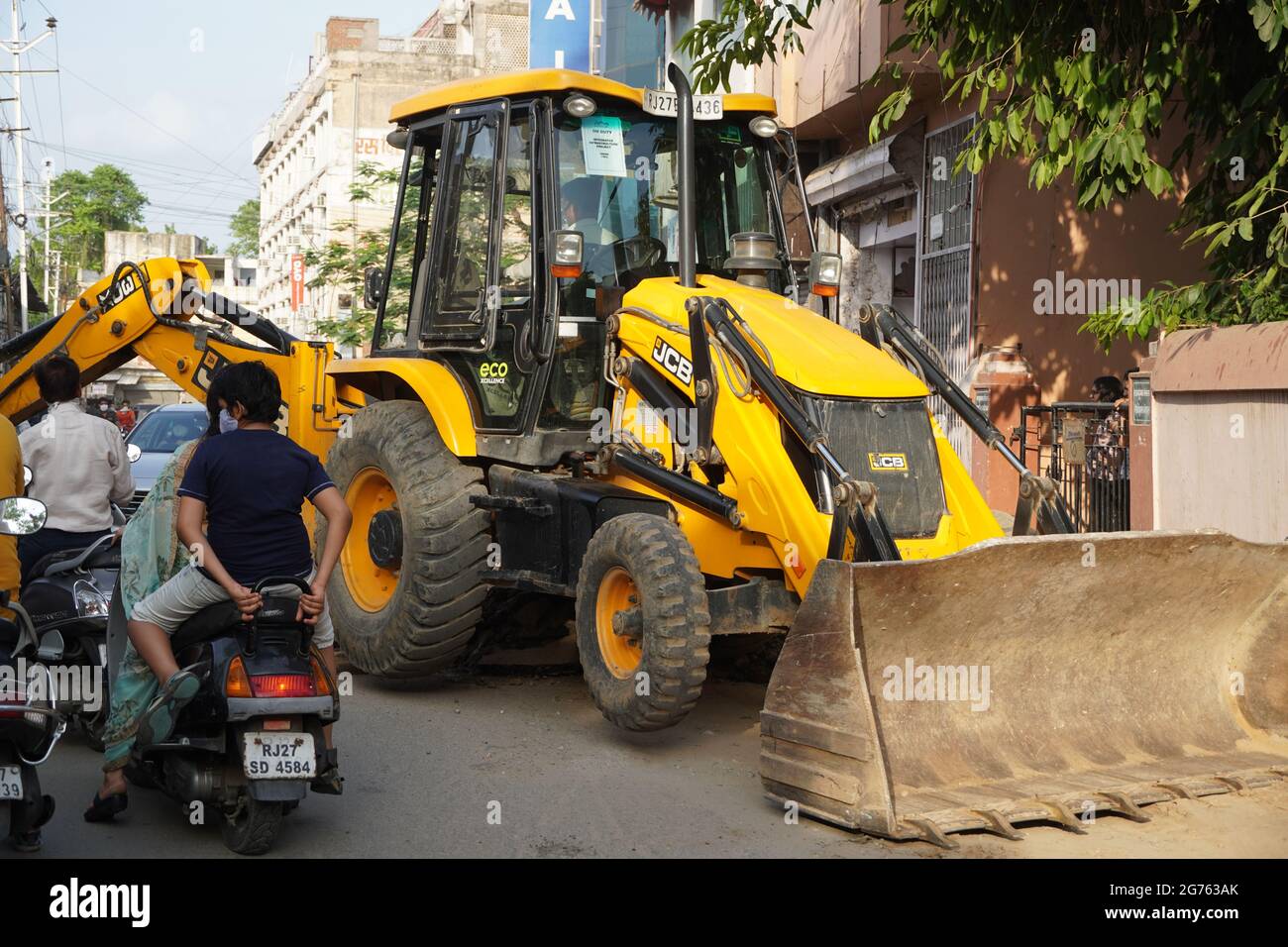 JCB Earth Moving Maschine, die auf einer Straße arbeitet. JCB-Schaufellader repariert einen Abschnitt einer unbefestigten Straße. Im Wohnviertel wächst die Straße. Thema o Stockfoto